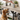 Dog eagerly waiting for a treat on a wooden shelf with decorative items.