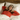 Woman wearing a red shirt and a sleep mask, lying in bed with white pillows and a wooden headboard.