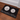 Black doormat with white illustrations of animals and people on a wooden floor.