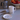 White mug and plate with black cat illustrations on a kitchen counter with a coffee maker and apples in the background.
