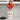 Person holding a red potholder with animal designs above a white compost bin in a kitchen.