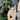 Cat sitting inside a green felt Christmas tree with colorful pom-poms.