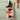 A beige canvas tote bag with black handles, featuring a whimsical print of two dachshunds wearing red-and-white striped outfits, hanging from a wooden ladder bar against a pale green wall. The bag is filled with groceries, including a loaf of bread, greens, and lavender.