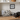 Dog playing with a bone on a mat next to a bag with dog pattern, with a shelf in the background.