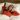 Woman wearing a red shirt and a sleep mask, lying in bed with white pillows and a wooden headboard.