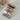 Four small sandal-shaped toys on a light gray surface with a box in the background.