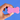 Hand holding a pink bone-shaped sponge against a blue background