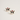 A pair of stud earrings shaped like French bulldog faces wearing red Santa hats with white faux pearls, shown on a clean off-white background.