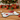 Dog bone-shaped mat with a red bowl of dog food on a wooden floor with Christmas decorations.