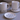 Two white mugs and two small plates with black line art designs on a gray surface.